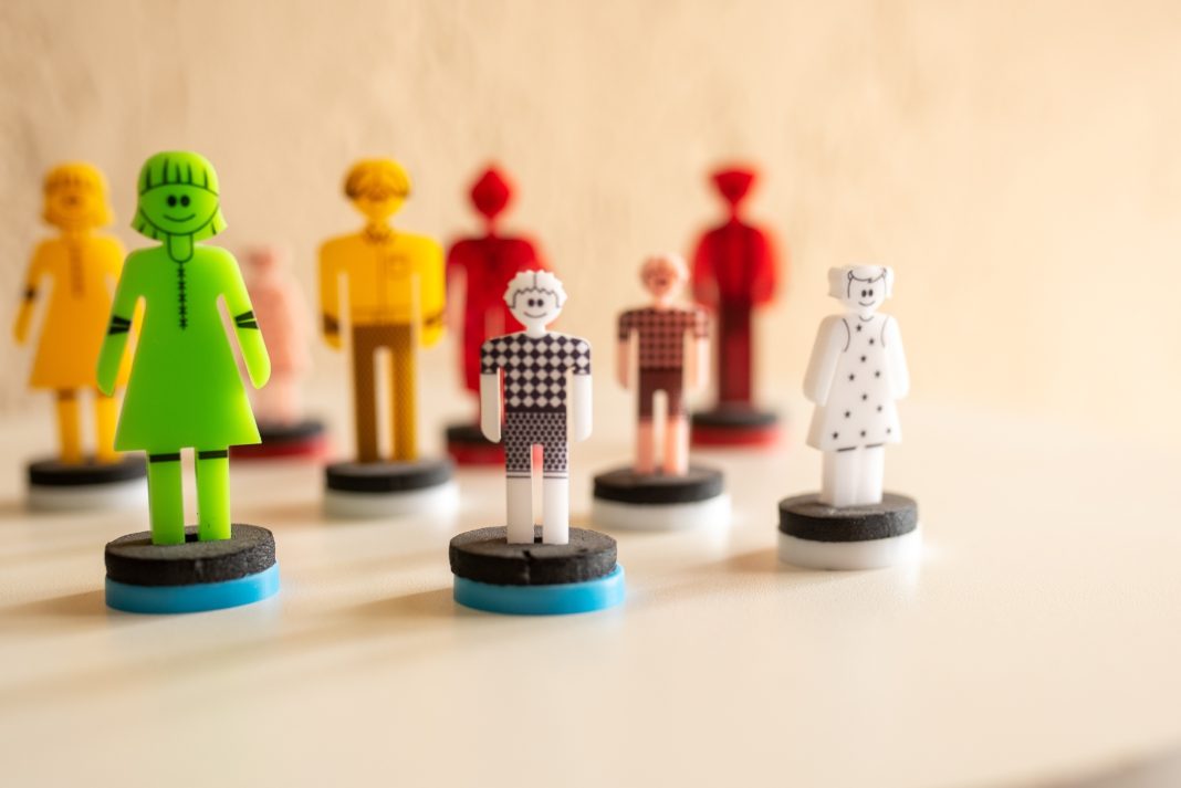A collection of colorful human-shaped plastic figures standing on small round bases on a light surface.